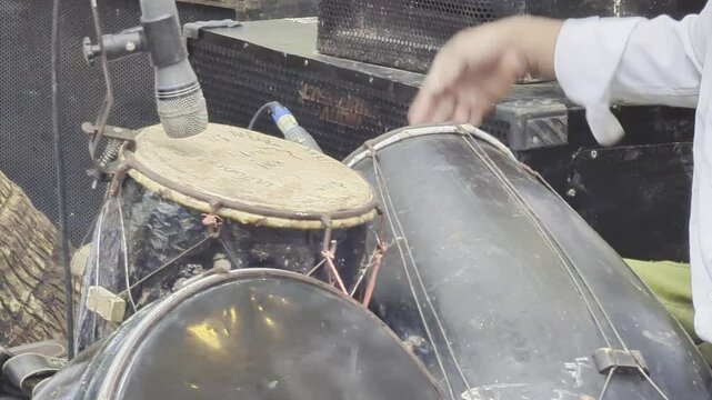 a musician playing kendang (a musical instrument from Javanese gamelan) which functions as a rhythm regulator in gamelan music, including tempo and song transitions