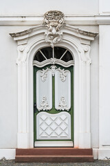A green door with white trim sits in front of a white building in Saarbrucken Germany