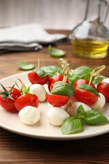 Appetizers with mozzarella, tomatoes and basil on wooden table, closeup