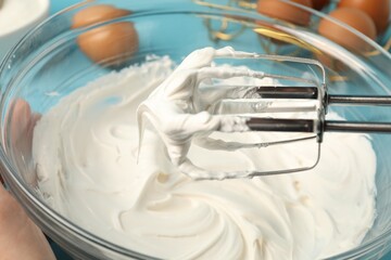 Whisking cream with hand mixer at table, closeup