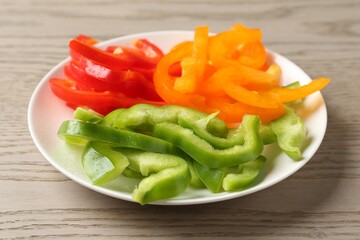 Slices of fresh colorful bell peppers on wooden table, closeup