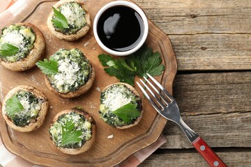 Tasty stuffed mushrooms served on wooden table, top view