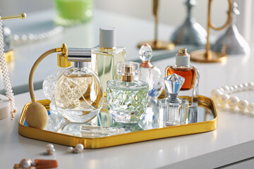 Bottles of different perfumes on white table indoors, closeup
