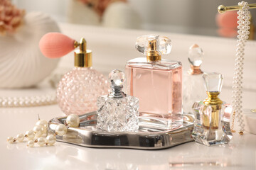 Bottles of different perfumes and accessories on dressing table indoors, closeup