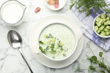 Tasty cucumber soup with dill and microgreens served on white marble table, flat lay