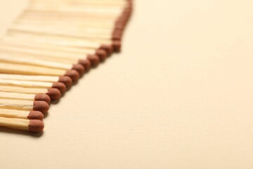 Matches with brown heads on beige background, closeup. Space for text