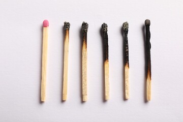 Burnt and whole matches on light grey background, flat lay