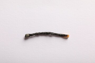 One burnt match on light grey background, top view