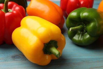 Fresh colorful bell peppers on blue wooden table, closeup