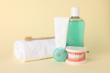 Different oral care products and dental model on beige background