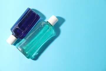 Bottles of mouthwash on light blue background, top view. Space for text