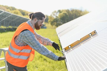 Technician installing solar panels in a solar farm using level tool