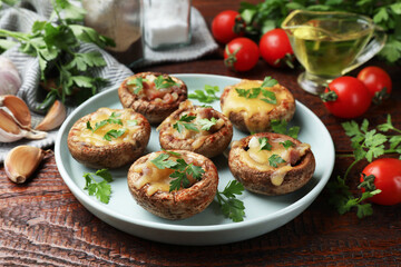 Fototapeta premium Tasty stuffed mushrooms and ingredients on wooden table, closeup