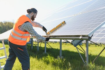 Worker installing solar panels using spirit level in solar farm