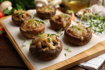 Delicious stuffed mushrooms with melted cheese and thyme on wooden table, closeup