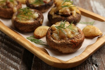 Delicious stuffed mushrooms with melted cheese, garlic and dill on color wooden table, closeup