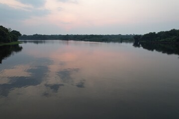 Calm waters reflect evening sky near lush greenery in a tranquil setting