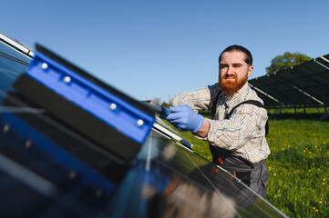 Worker cleaning solar panels in a solar farm for green energy production