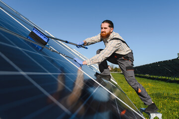 Worker cleaning solar panels in a solar farm for green energy production