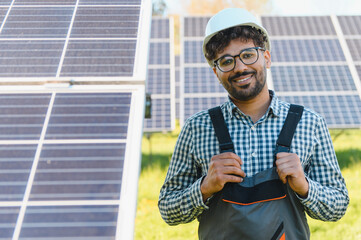 Smiling Arab engineer installing solar panels in a solar farm