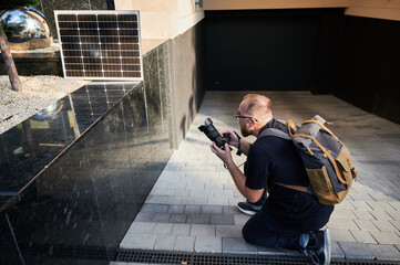 Bearded male photographer capture shot, with solar panel charging nearby. Concept of use of sustainable renewable energy, eco-friendly practices in creative work. Solar power for eco-friendly charging