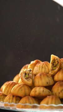 The pastry chef sprinkles powdered sugar over the pistachio-filled sweets