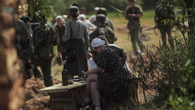 World War 2 reconstruction. German occupation in countryside. Waffen SS troops and Helferinnen round up locals residents civilians, collaborators observe actions of punitive squad. Reenactment show