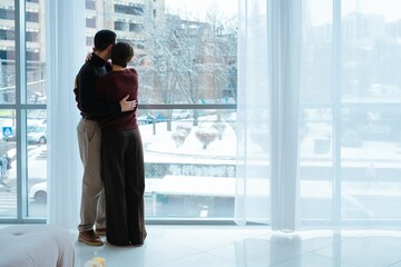 Couple enjoying a snowy city view from a cozy indoor setting