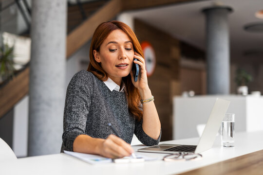 Professional Woman Multitasking While On a Phone Call in a Modern Office