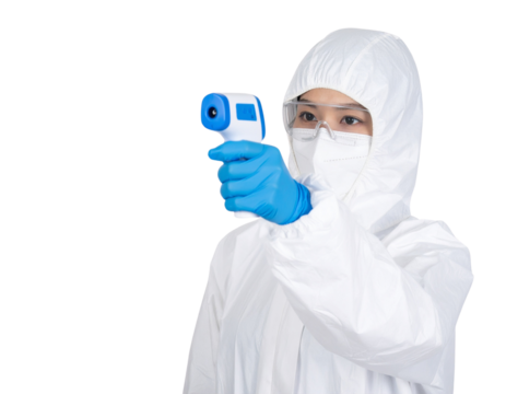 A healthcare worker in full protective gear holds a digital infrared thermometer aimed forward for temperature screening.