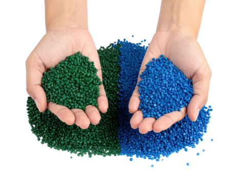 Two hands holding blue and green plastic pellets used for manufacturing and molding processes.