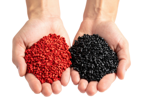 Two hands are holding small red and black plastic pellets used in manufacturing and industrial processes.