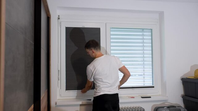 Man installing pleated blinds on an interior window