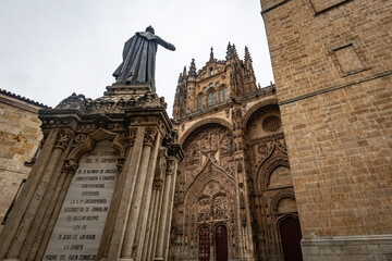 Statue of Fray Luis de LeÃ³n standing before the ornate facade of the New Cathedral of Salamanca,...