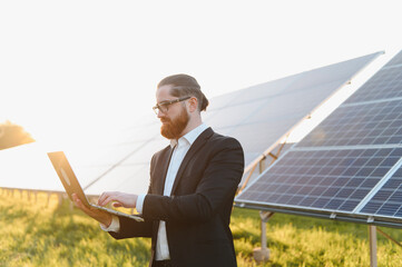 Businessman using laptop analyzing solar panel farm investment