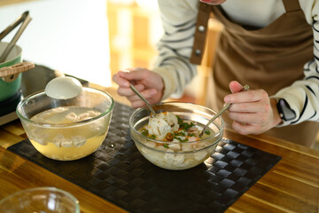 Close up of a man preparing a bowl of hot noodle soup in a cozy kitchen