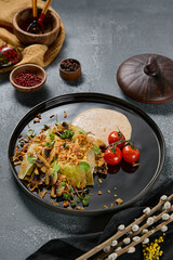 Cabbage steak with mushrooms and crispy onions plated on black, overhead composition, vibrant food styling