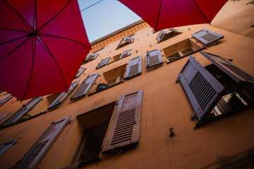 Beautifully decorated window of an old house. Window with open shutters and beautiful decor among red umbrellas decorating the street of an old town