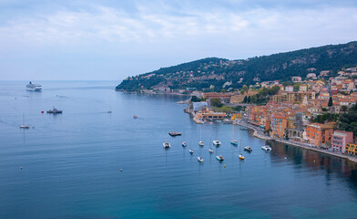 Fototapeta premium Panoramic view of the seaside resort town in France. Villefranche-sur-Mer, embankment with boats and blue crystal clear water of the sea