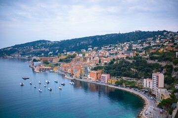 Fototapeta premium Panoramic view of the seaside resort town in France. Villefranche-sur-Mer, embankment with boats and blue crystal clear water of the sea