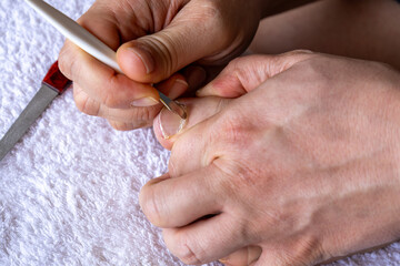 Close-up of a person gently pushing back the cuticles on their toenails using a metal cuticle...