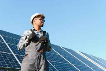 Technician adjusting overalls while inspecting solar panel farm