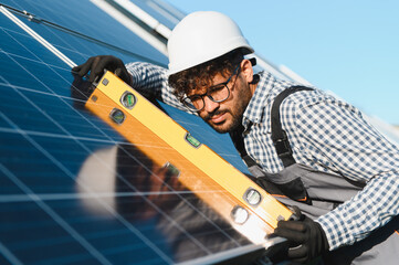Engineer installing solar panel using level tool on roof