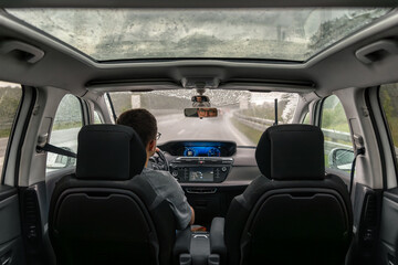 Driving in rainy weather. Modern car interior. Rear seat perspective.