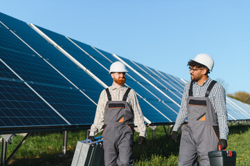 Engineers walking in solar panel farm carrying tools