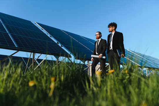 Investors walking and discussing next to solar panels in sustainable energy plant