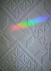 Rainbow light reflection on white wall with geometric pattern background