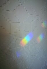 Rainbow light reflection on white wall with geometric pattern background