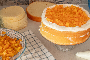 cooking homemade cake with peach filling. vanilla round sponge cakes with cream and peaches inside. making homemade holiday dessert recipe with fruits. High quality photo