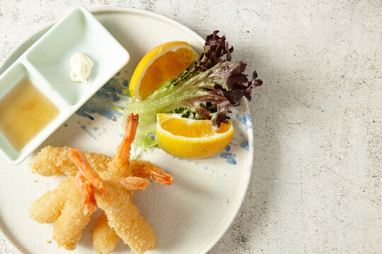 ebi tempura with lemon, soy sauce, mayonnaise and lettuce on a white plate
